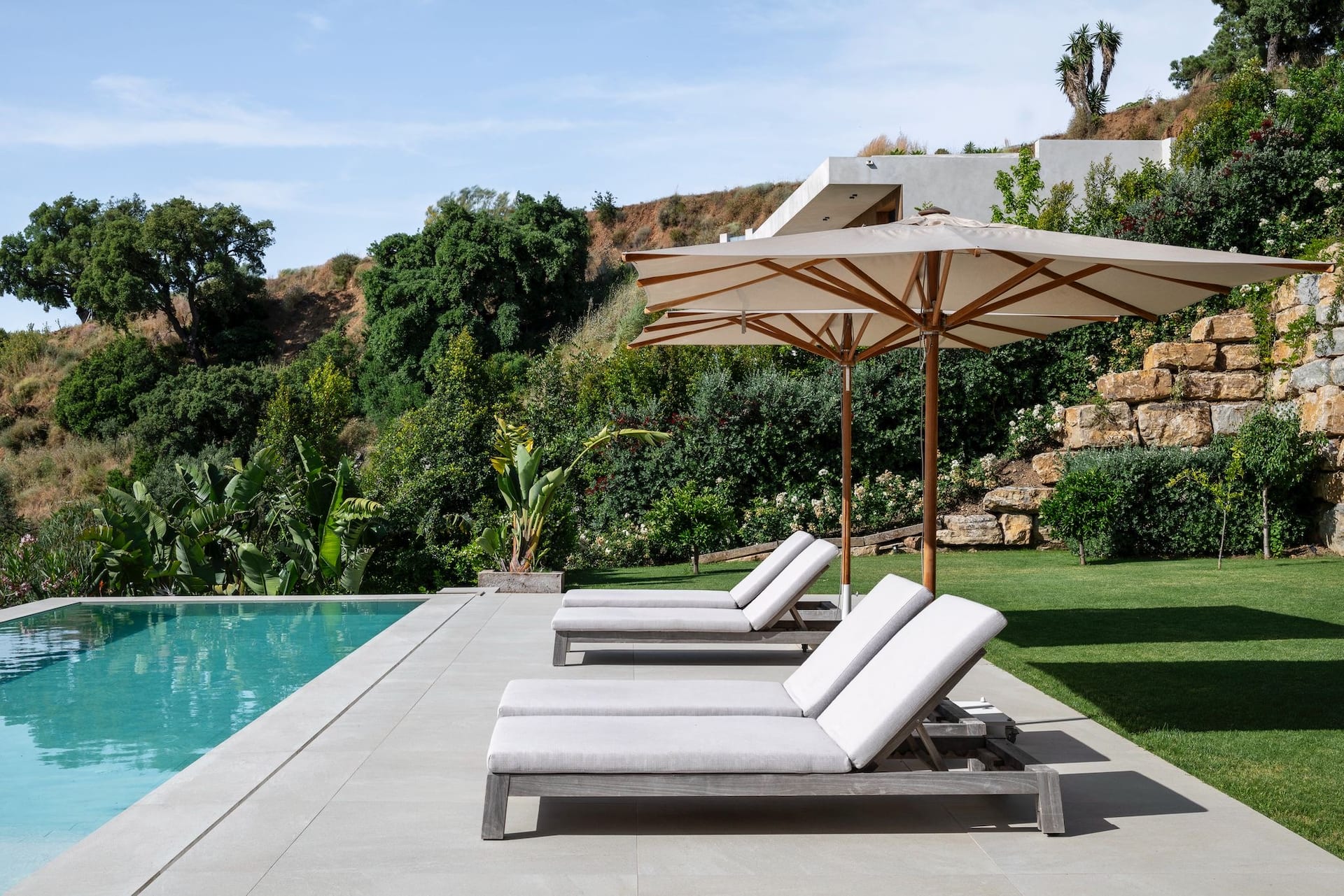 Villa Sesa: designvilla met infinity pool en zeezicht in Benahavís 8 Ligbedden aan het zwembad tussen het groen